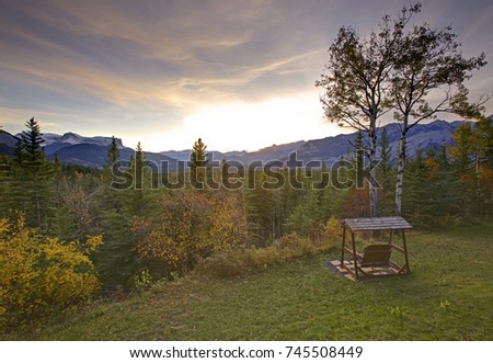 a beautiful evening sunset over wooden swings with the canadian rocky mountains in behind 