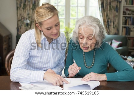 Woman Helping Senior Neighbor With Paperwork Royalty-Free Stock Photo #745519105