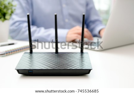 Wireless router and man using a laptop in office. router wireless broadband home laptop computer phone wifi concept Royalty-Free Stock Photo #745536685