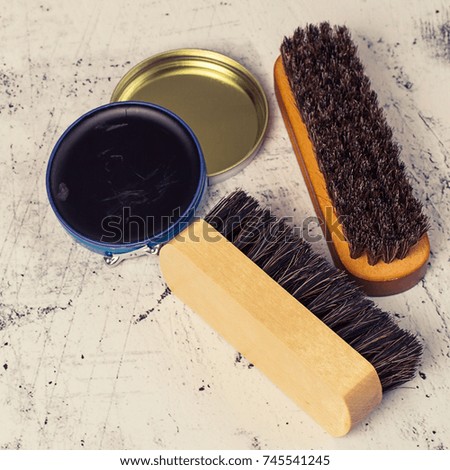       Care products for footwear. Brushes for cleaning shoes and an open jar with cream on a light background. Toned photo.