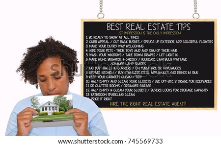 Woman holding photo of home in front of Real Estate Tips Blackboard Woman holding photo of suburban home