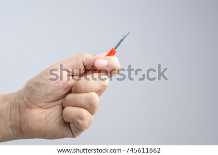 Hand holding seam ripper or thread picker on white background