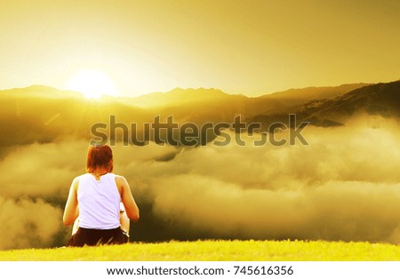 woman sit alone on the mountain with the sunrise and fog on sky