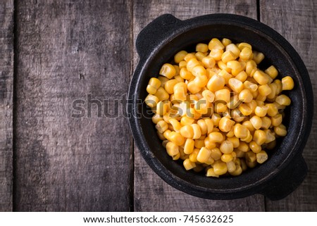 Sweet corn kernels in bowl on wooden table . Cooked canned yellow vegetable, vegetarian staple food.