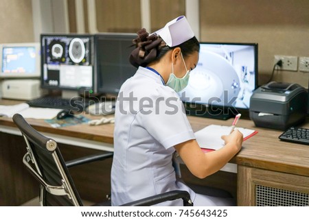 Nurse record vital sign into medical chart at computed tomography(CT scan) workstation room.