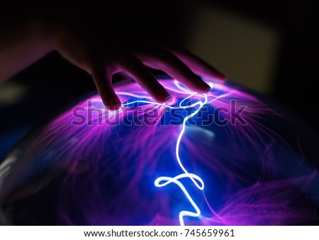 Woman's hand touching plasma globe. Royalty-Free Stock Photo #745659961