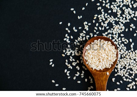 Organic natural sesame seeds wooden spoon. toasted sesame seeds. Raw, whole, unprocessed. Natural light. Selective focus. Close up on a black background. Top view, flat lay. copy space for text. Royalty-Free Stock Photo #745660075
