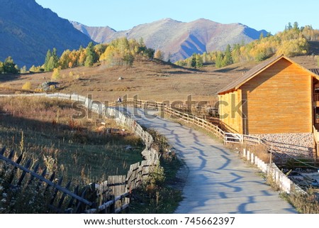 At the Twilight Hemu Village, the wooden building of the road on the second side of the road, the fence of the hill slope The road and the distant mountain form the beautiful picture.