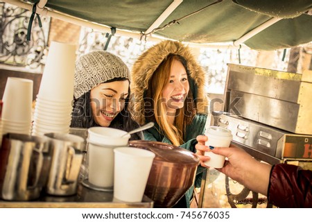 Happy girlfriends best friends sharing time together outdoors at coffee takeaway vendor in winter season - Women friendship concept with joyful girls having fun on deep clothes - Warm vintage filter