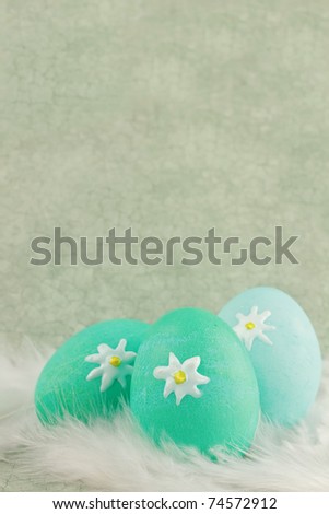 Easter eggs in a nest of feathers against a green vintage background with room for copy space. Extreme shallow DOF.