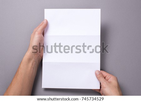 Man holds an open blank letter mock-up and on a gray background