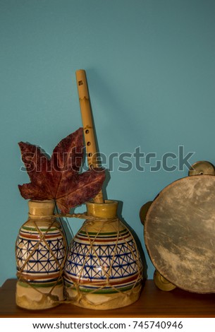 Ethnic instruments: drum, flute and tambourine with dry leaf on blue background.