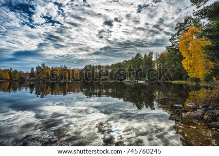 Picture of blue sky over autumn lake with stones in the water.