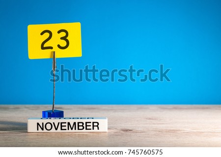 November 23rd. Day 23 of november month, calendar on workplace with blue background. Autumn time. Empty space for text