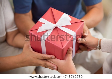 Close up on hands. Asian Boy giving a red gift box to his Grandfather and Grandmother for Birthday, Christmas and New year at their house.