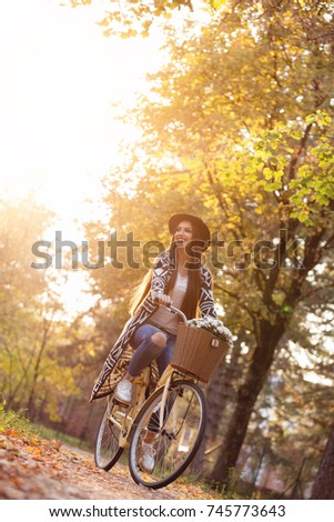 Happy woman riding bike bicycle in fall autumn park