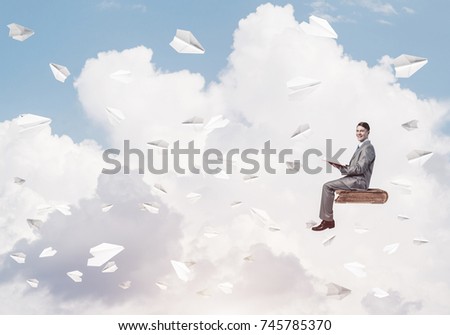 Young businessman sitting on floating in air book with one in hands