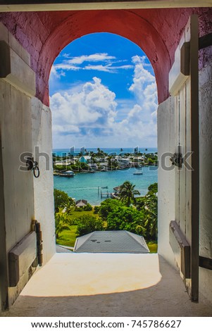 Beautiful view from a window of Elbow Reef Lighthouse with blue sky, white clouds, harbour and Caribbean sea in Hope Town, Marsh Harbour, Abaco, The Bahamas.
