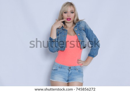 Beautiful blond young woman in pink tank top and jeans costume with shorts and jacket posing and look to camera. Horizontal photos.
