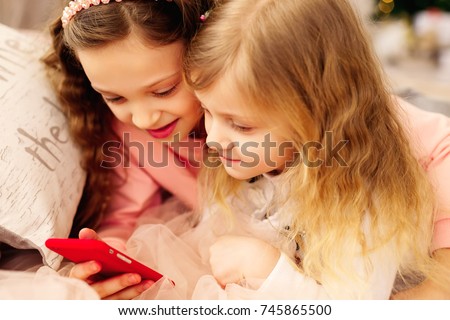Two happy girls are delighted to see photos on their mobile phone