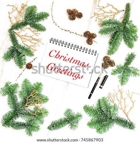 Christmas decoration and open book on marble stone texture. Pine branches with golden ornaments. Sample text Christmas Greetings