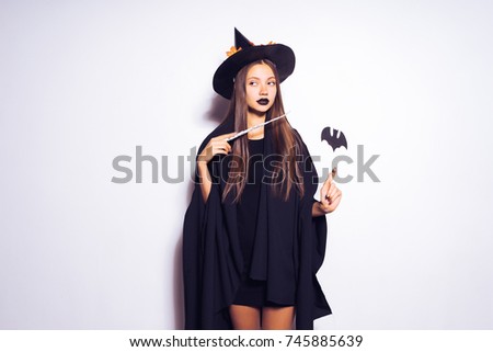 beautiful gothic mysterious girl in the image of a witch holding a magic wand in her hand