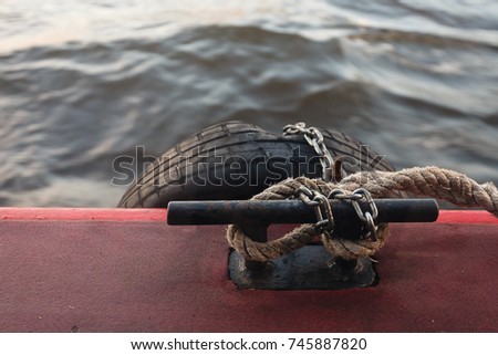 Mooring rope and bollard on water background. Mount suitable for mooring the vessel on the background of the river surrounded by the city and bridges.