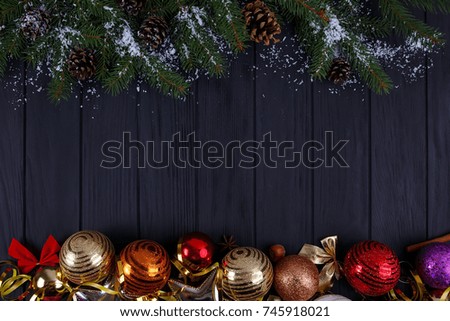 Christmas, New year holidays composition of festive decorations, cones, snow-covered fir tree branches, baubles on black wooden background with copy space for your text design