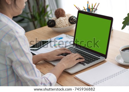 Over the shoulder shot of a woman typing on a computer laptop with a key-green screen. Woman hand typing laptop with green screen.
