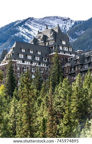 Canadian mountain hotel in the trees with snowy mountains in the background