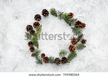 Winter pattern with spruce branch, cones and clean sheet on grey background top view copyspace