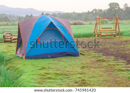 Tents on green grass at dawn with benches and swings around, background, sky, trees and mountains, Chiang Mai, Thailand.