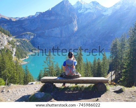 Asain man is take photo at the unique lake - Oeschinen (Oeschinensee), UNESCO World Heritage Site. Beautiful outdoor scene in Bernese Oberland Alps, Switzerland, Europe.