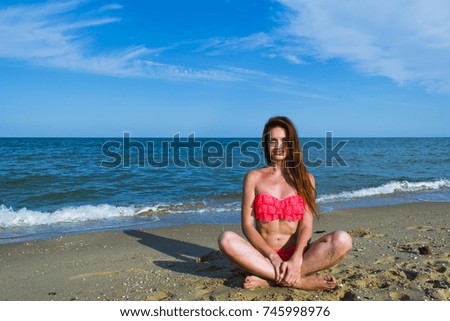 Woman in pink bathing suit on the beach, near the sea smiling