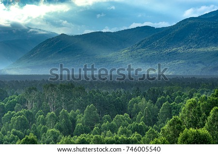 Dramatic sunrise in the mountains with thick evergreen forest in foreground, Altai Mountains, Kazakhstan Royalty-Free Stock Photo #746005540