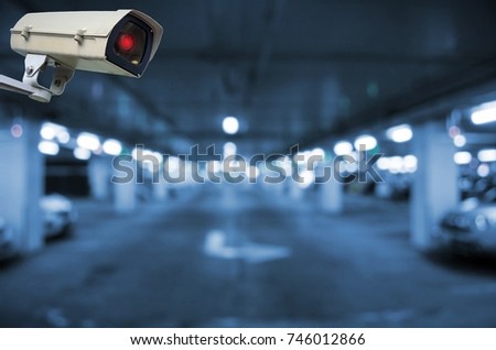 CCTV, security indoor camera system operating in underground car parking garage area, blue color tone, surveillance security and safety technology concept