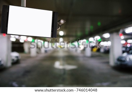 CCTV and LCD TV with white blank screen or billboard for your text message or media content with blurred image of intelligent car parking garage area, advertising, commercial and marketing concept