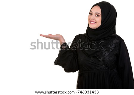 studio shot of young woman wearing traditional arabic clothing. she's holding her hand to the side Royalty-Free Stock Photo #746031433