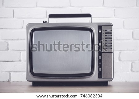 Old television on a white brick wall background.Vintage styls color .