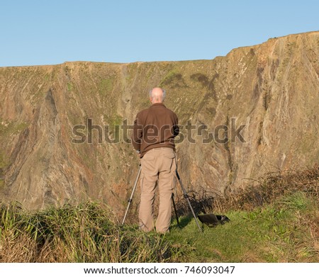 Elderly Male Photographing the Dramatic Cliffs at Hartland Quay on the Atlantic Coast in North Devon, England, UK