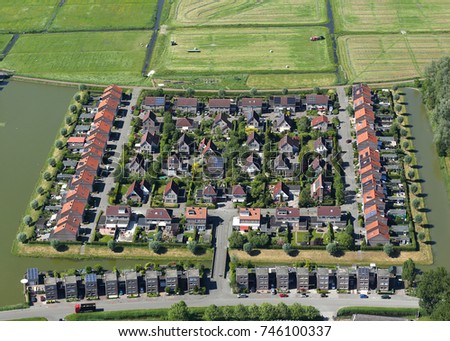 Aerial view of residential area. The block is surrounded by water and green fields.