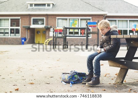 sad boy outside at schoolyard Royalty-Free Stock Photo #746118838