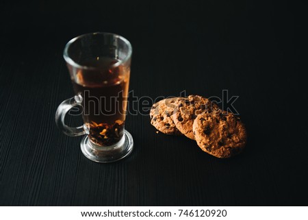 Oatmeal cookies with chocolate chips. Cookies with a Cup of tea on a black background
