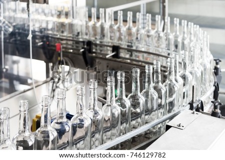 Empty glass bottles on the conveyor. Factory for bottling alcoholic beverages. Royalty-Free Stock Photo #746129782