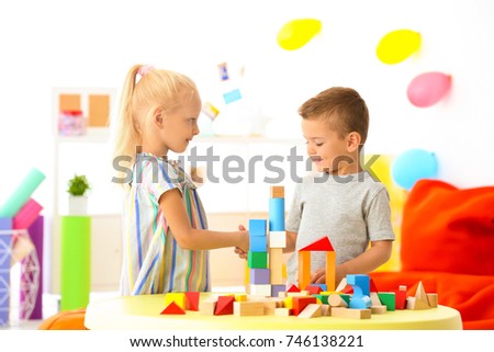 Cute children playing with blocks on table indoor