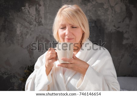Morning of beautiful mature woman drinking coffee at home