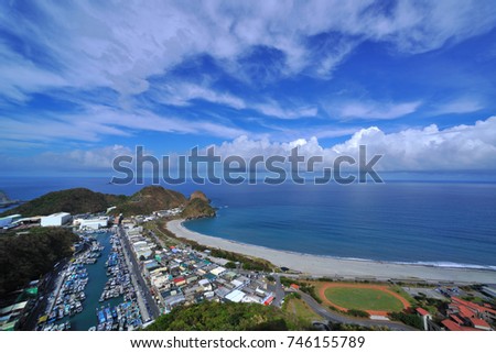 On the east coast of Taiwan, the curved beaches, the boats are neatly arranged in the fishing port, the houses along the road, the blue sky and the white clouds are bright and dazzling.