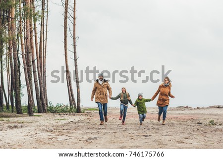 happy family running together and holding hands on nature