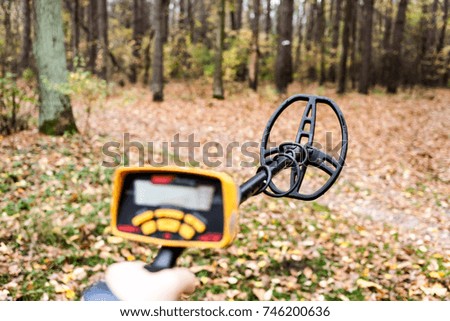 Man with electronic metal detector device working on outdoors background. Close-up photography of searching process.