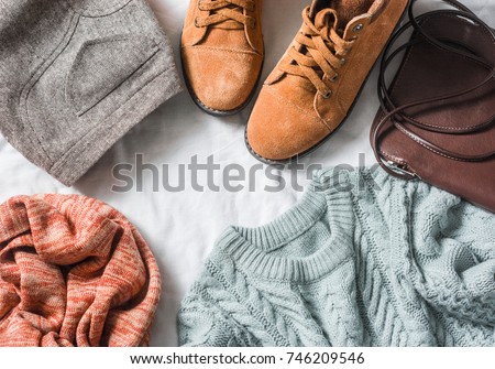 Women's clothing set - skirt, suede boots, sweater, scarf, leather cross body bag on a light background, top view. Winter, fall female clothing   